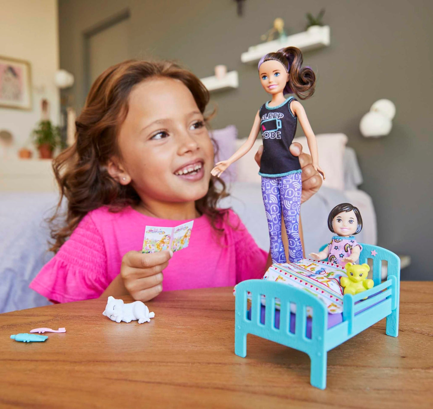 Barbie Skipper Babysitters Inc. playset featuring toddler doll in glow-in-the-dark pajamas with bed, kitty, teddy bear, and storybook.