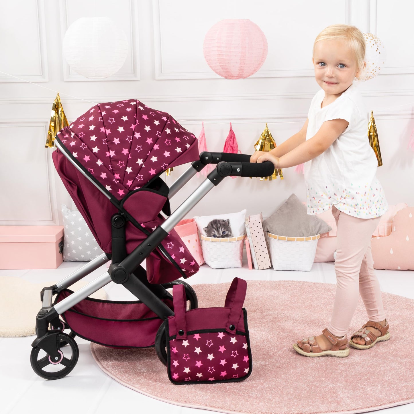 Bayer Baby Dolls Pram XEO in burgundy and pink stars, convertible doll pushchair with carrycot, changing bag, and adjustable handle.