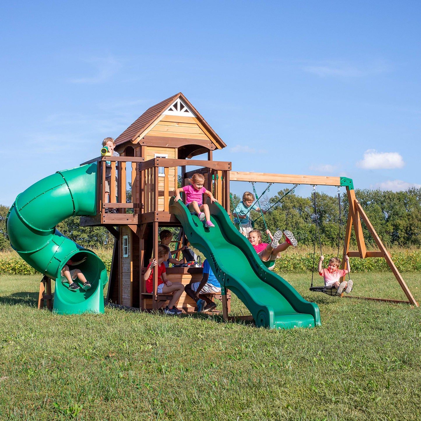 Backyard Discovery Cedar Cove cedar wood swing set with wave slide, tube slide, climbing wall, web disc, and belt swings for kids.