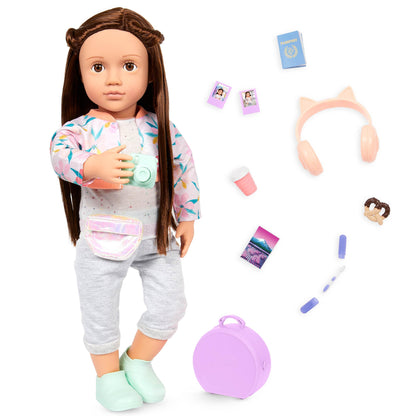 Our Generation posable 18-inch doll Reese with brown eyes and long hair, accompanied by carry-on luggage and travel accessories.