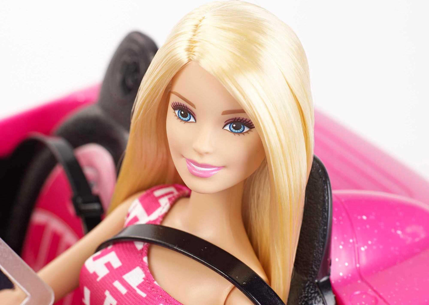 Barbie playset with sparkly pink 2-seater convertible car, fashion doll in sundress and sunglasses, featuring glam details.