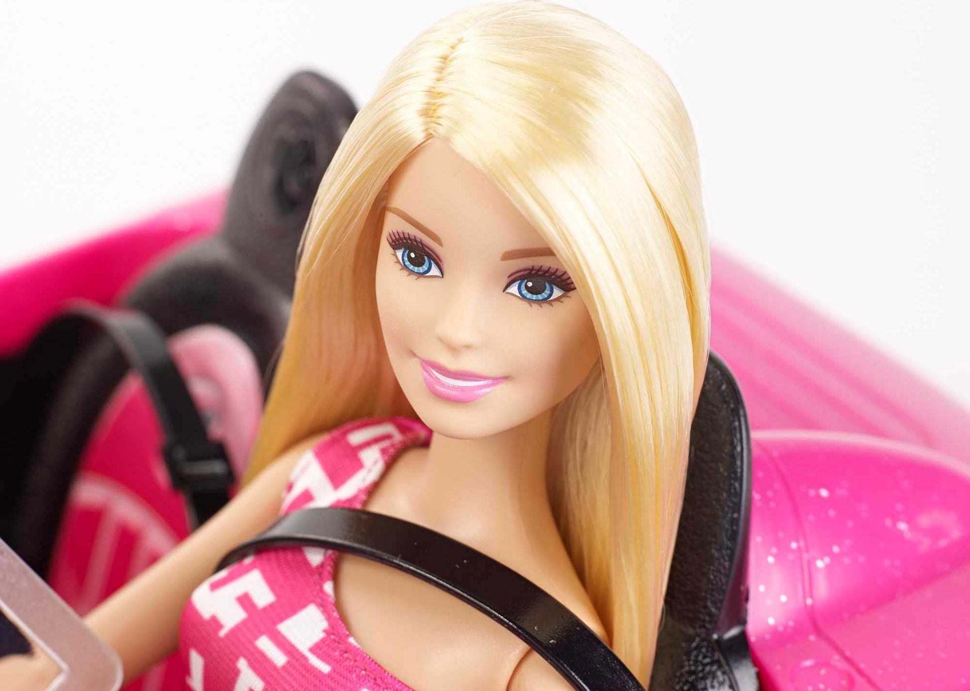 Barbie playset with sparkly pink 2-seater convertible car, fashion doll in sundress and sunglasses, featuring glam details.
