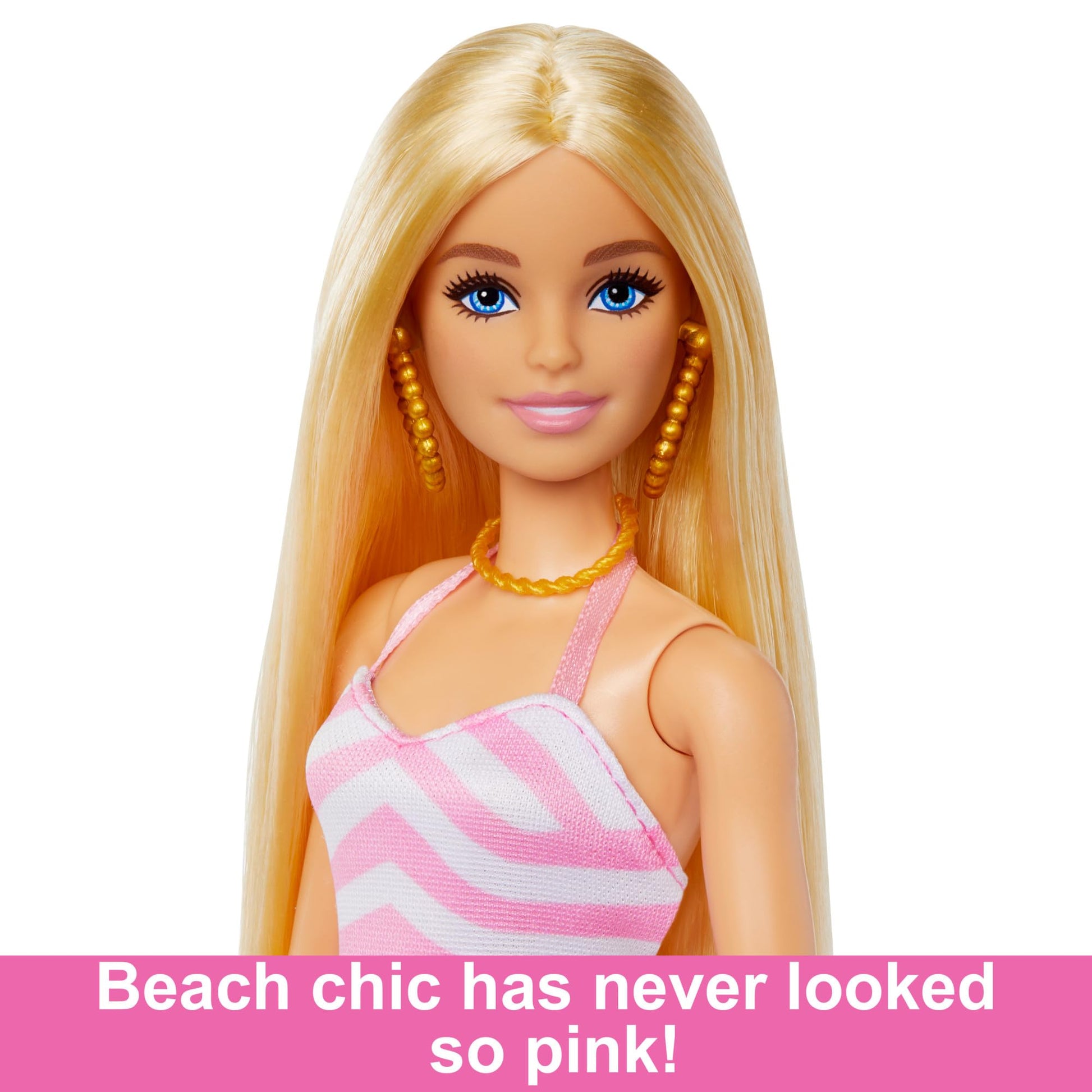 Blonde Barbie doll in pink and white swimsuit, sun hat, tote bag, and beach accessories on a sandy beach backdrop.