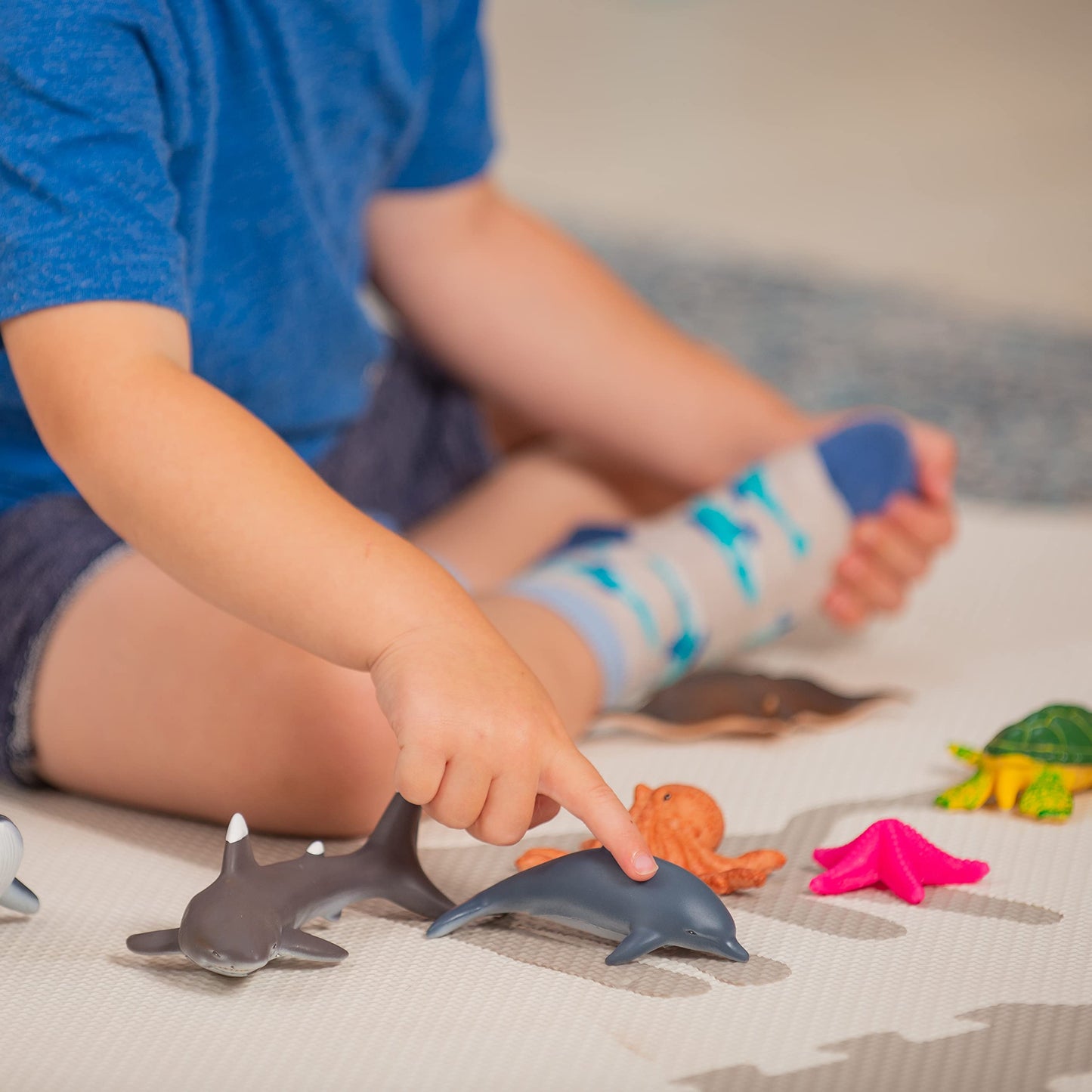 Set of 7 colorful Learning Minds sea animal figures including shark, whale, and dolphin toys for children aged 18 months and up.