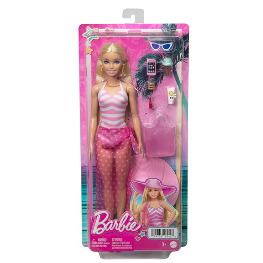 Blonde Barbie doll in a pink and white swimsuit wearing a sun hat, with a tote bag and beach-themed accessories.