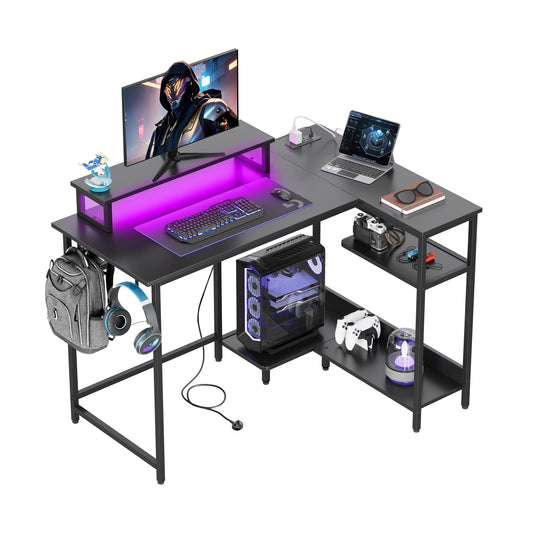 DEVAISE L-shaped gaming desk in black with monitor stand, RGB LED lights, power outlets, hook, and storage shelf for home office.