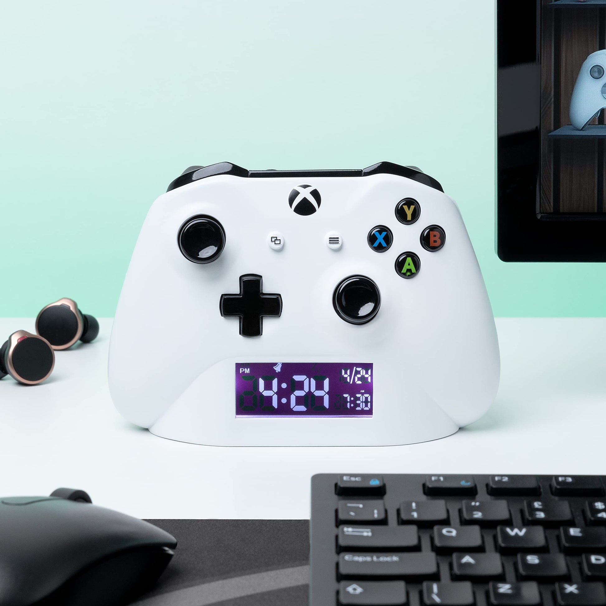Paladone Xbox alarm clock displaying multicolored lighting and digital time on a sleek gaming-themed design.