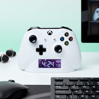Paladone Xbox alarm clock displaying multicolored lighting and digital time on a sleek gaming-themed design.