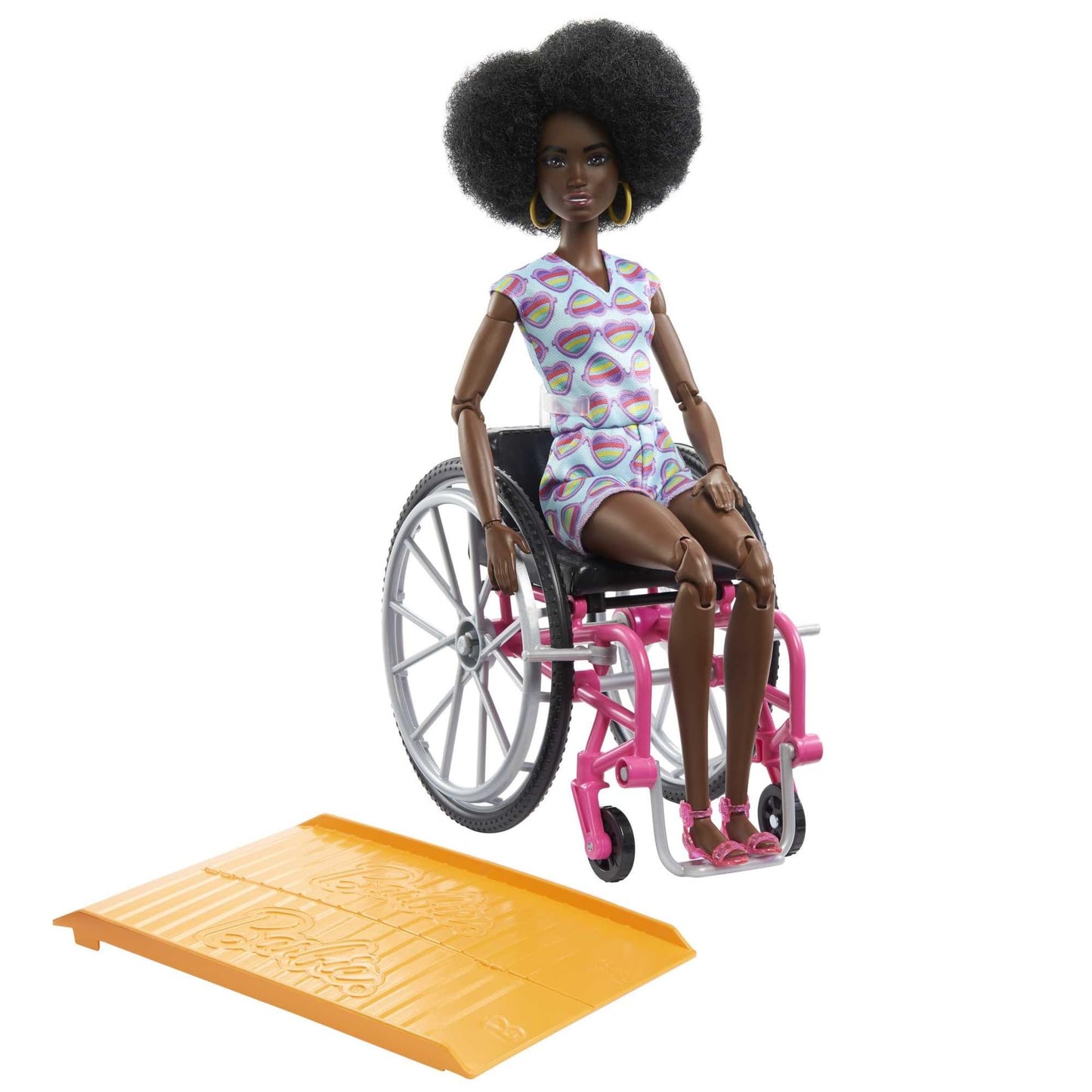 Barbie Fashionistas doll with curly black hair in rainbow heart romper, seated in wheelchair with ramp and accessories.