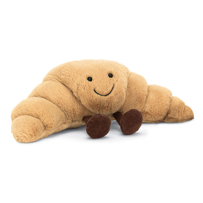 Jellycat Amuseable Croissant plush toy in soft fabric, measuring 10 cm tall and 33 cm wide, with a friendly face.