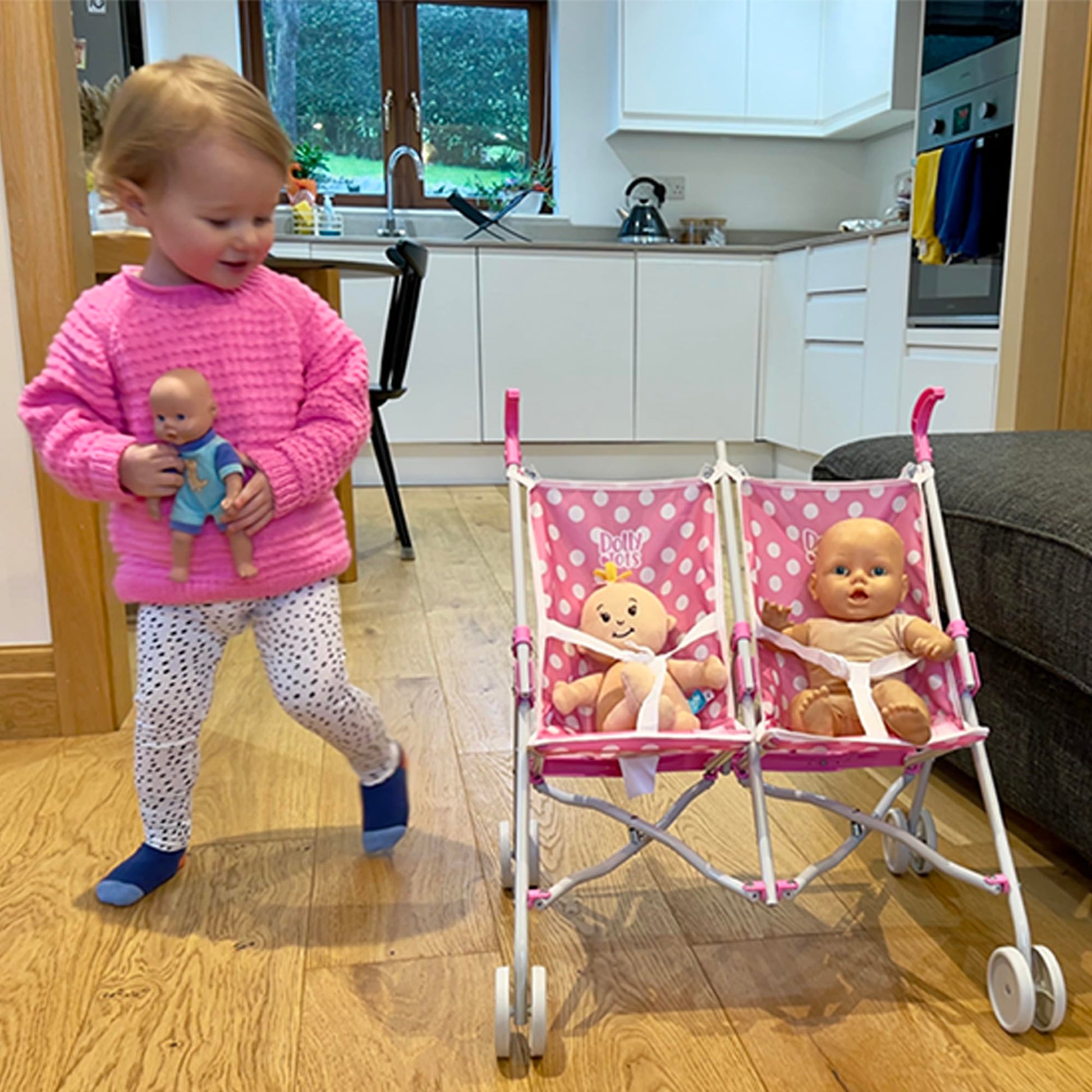 Pink Dolly Tots twin stroller with polka dots, lightweight umbrella fold design, ideal for kids age 2+ for role play and outdoor fun.
