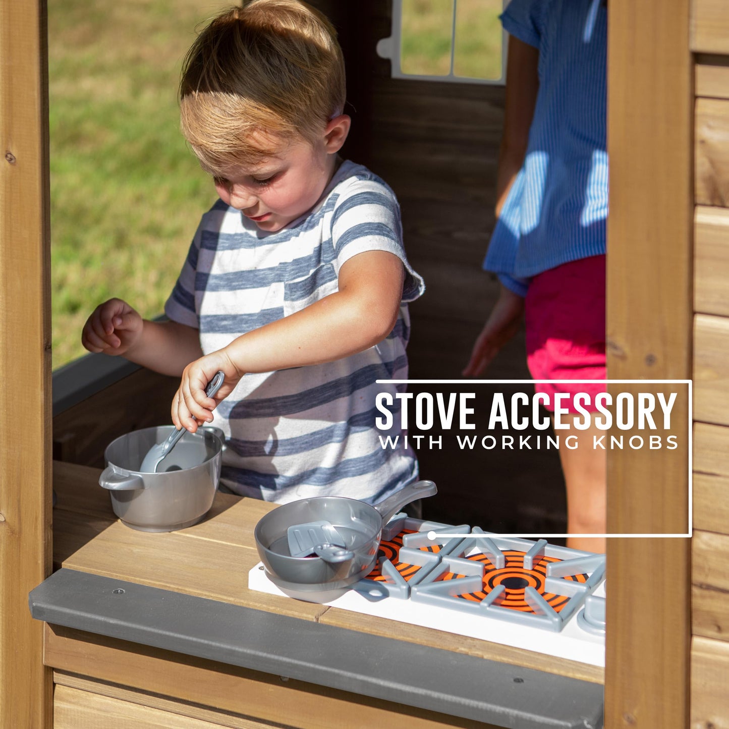 Backyard Discovery cedar wood children's playhouse with play kitchen, snack bar window, and half door in backyard garden setting.