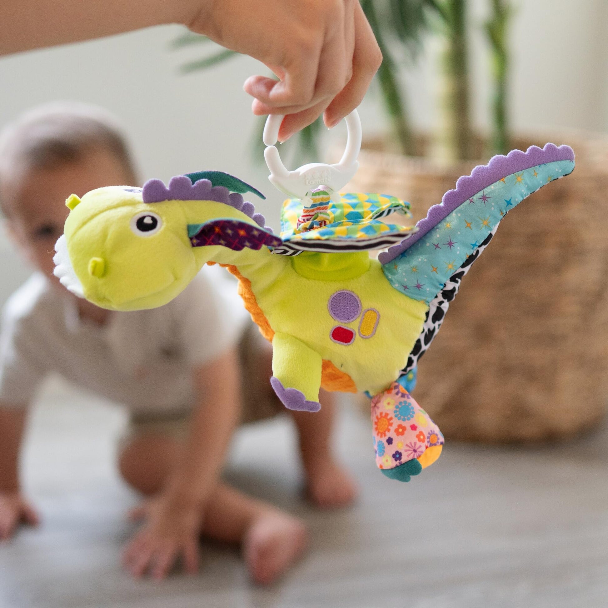 LAMAZE Flip Flap Dragon sensory clip toy attached to a baby stroller, designed for newborns 0-6 months to promote sensory play.