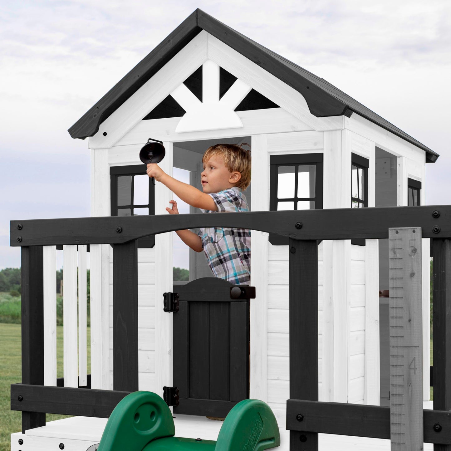 Backyard Discovery Sweetwater Heights cedar wood kids' playhouse with wave slide, toy kitchen, and growth chart in a garden setting.