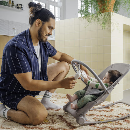 Bebeconfort Aster baby rocker with adjustable backrest, removable toy arch, 3-point harness, lightweight design, in tinted graphite.