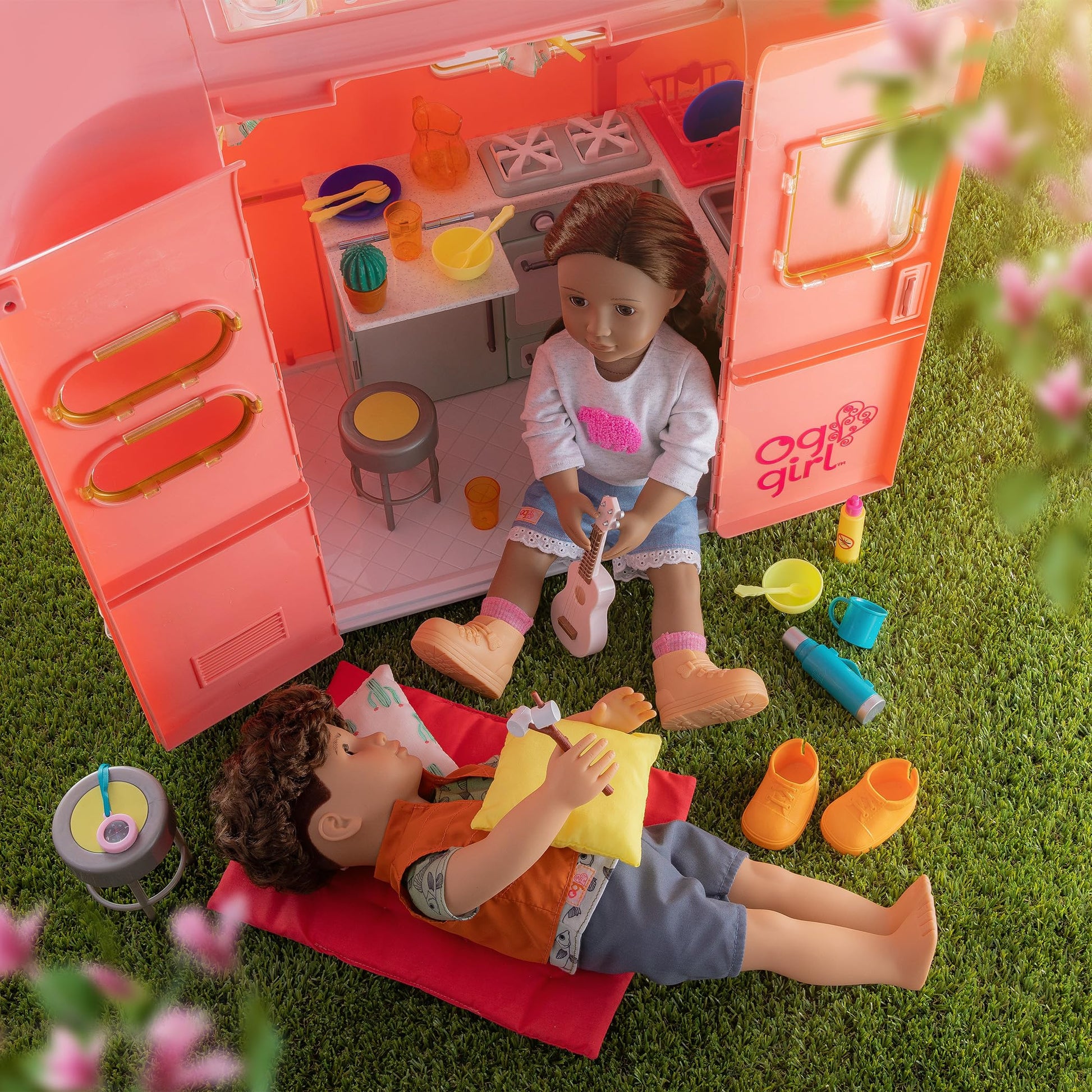 Our Generation pink camping trailer with kitchen and cooking accessories for 18-inch dolls, perfect for pretend play.