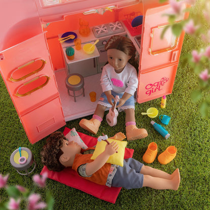 Our Generation pink camping trailer with kitchen and cooking accessories for 18-inch dolls, perfect for pretend play.