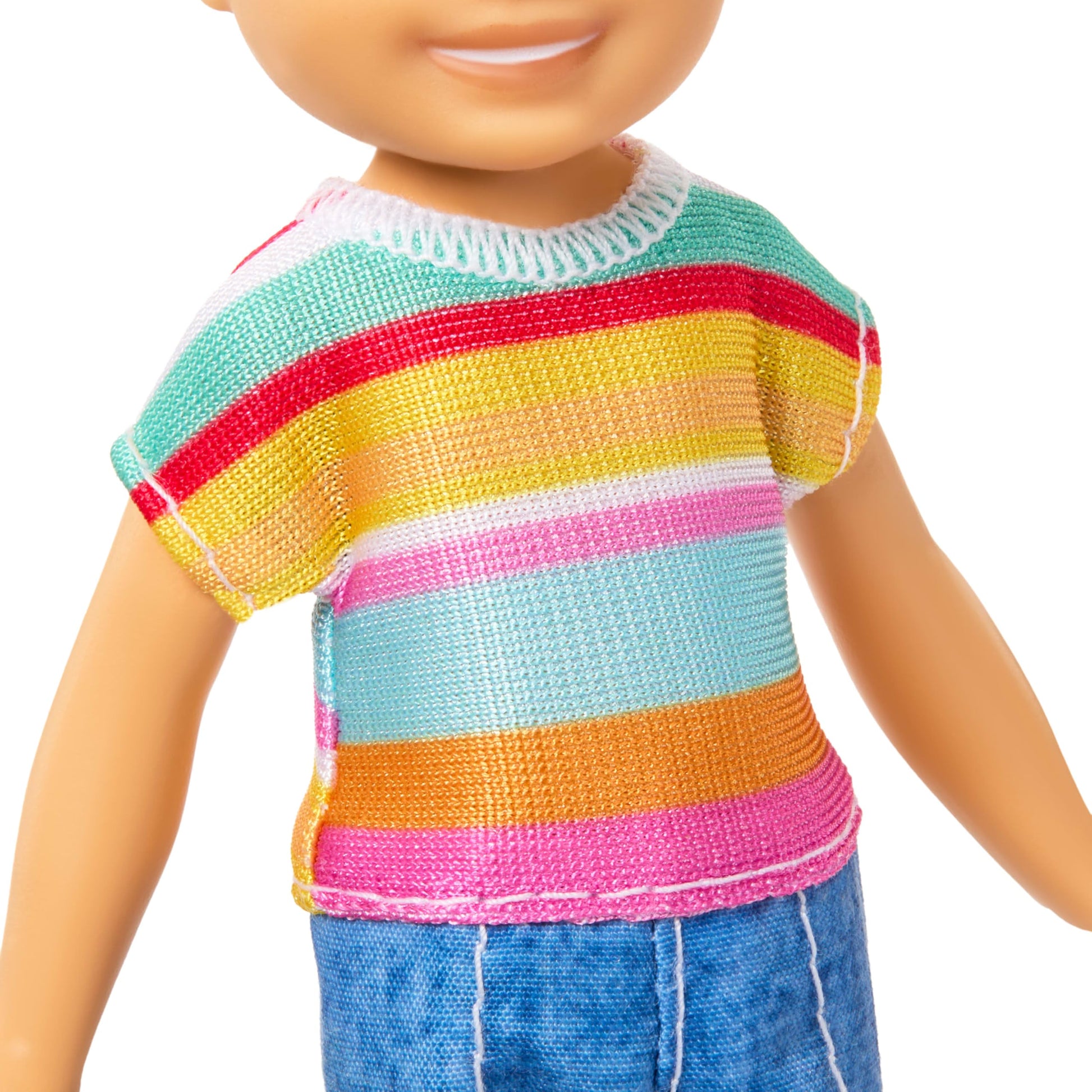 Barbie Club Chelsea Koji 6-inch boy doll with brunette hair, striped shirt, shorts, and shoes, posing with arms raised.