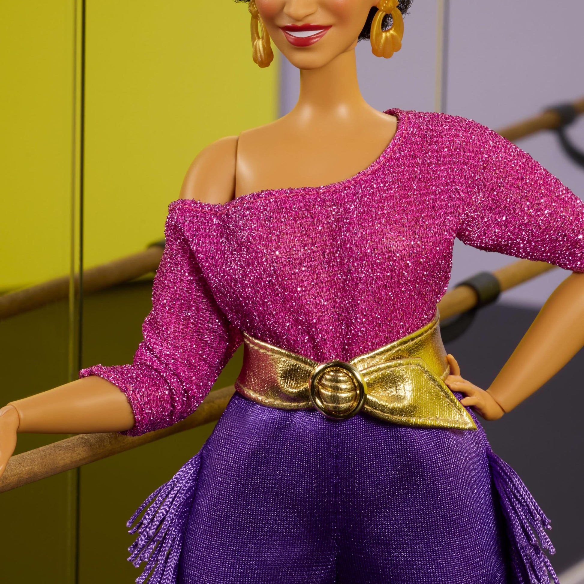 Barbie Signature Debbie Allen Tribute Doll wearing off-shoulder top, gold belt, purple fringe pants, and leg warmers.