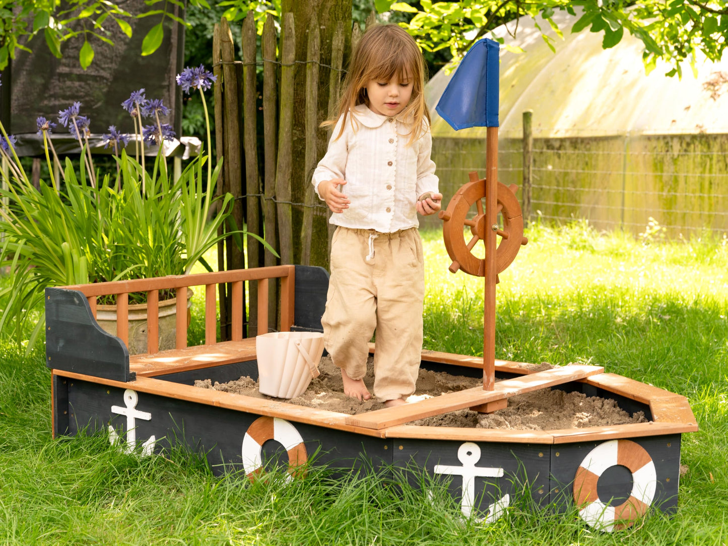 AXI Doris wooden boat-shaped sandbox with bench, storage, rotating rudder, cover, and ground cloth for kids' outdoor play.