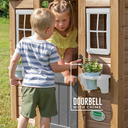 Backyard Discovery cedar wood children's playhouse with play kitchen, snack bar window, and half door in a backyard setting