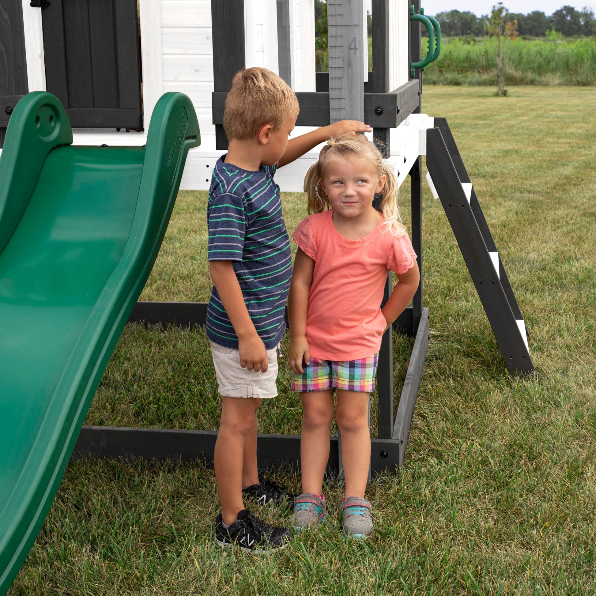 Backyard Discovery Sweetwater Heights cedar wood kids' playhouse with wave slide, toy kitchen, growth chart, outdoor garden structure.