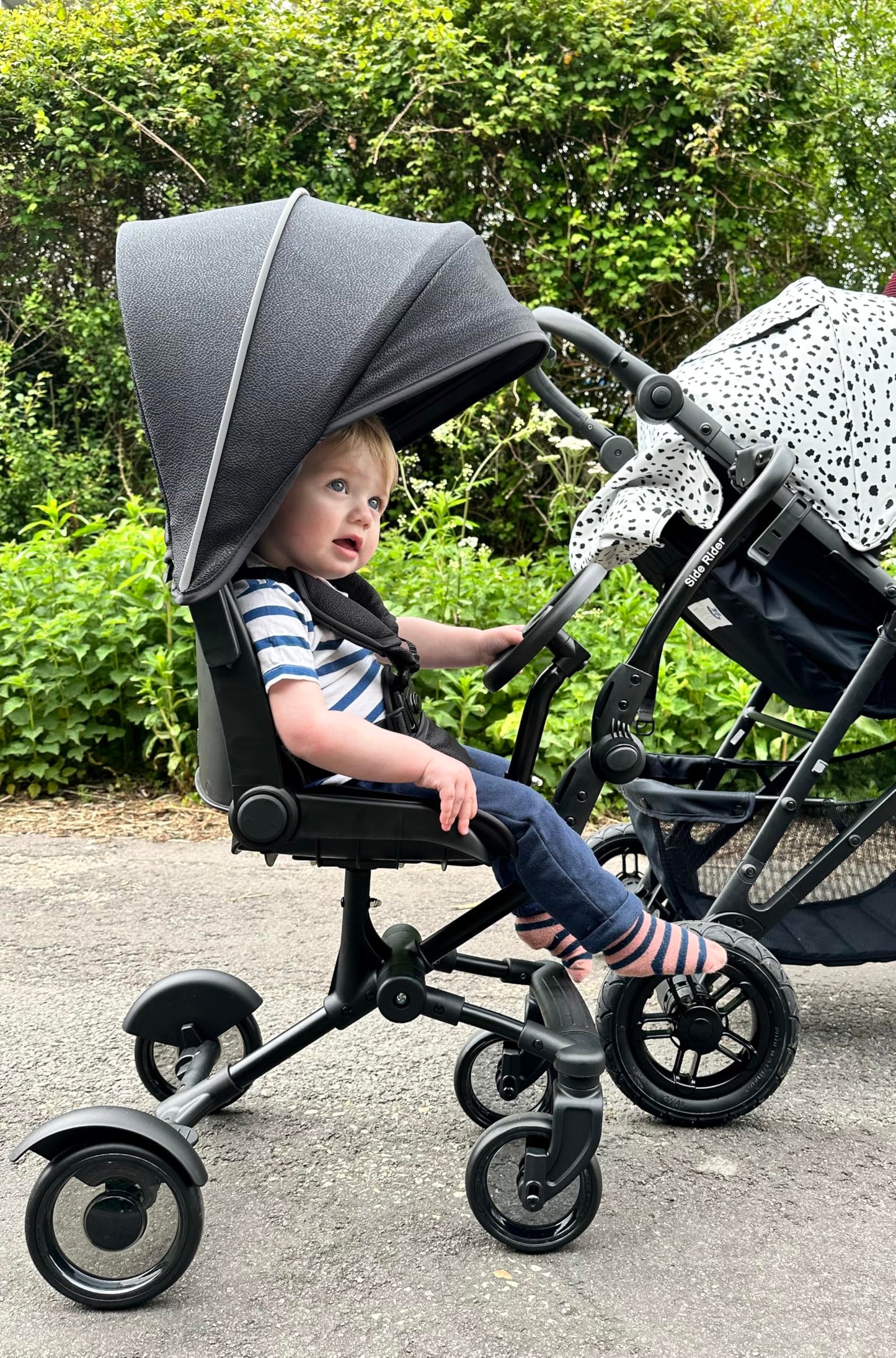 Roma Side Rider Universal Buggy Board with Seat - 4-Wheel Pram Board for Toddlers, Side Buggy Board with Universal Connector for Easy Attachment - Toy Steering Wheel - Hood